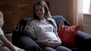 玩耍的男孩和怀孕的母亲坐在扶手椅上